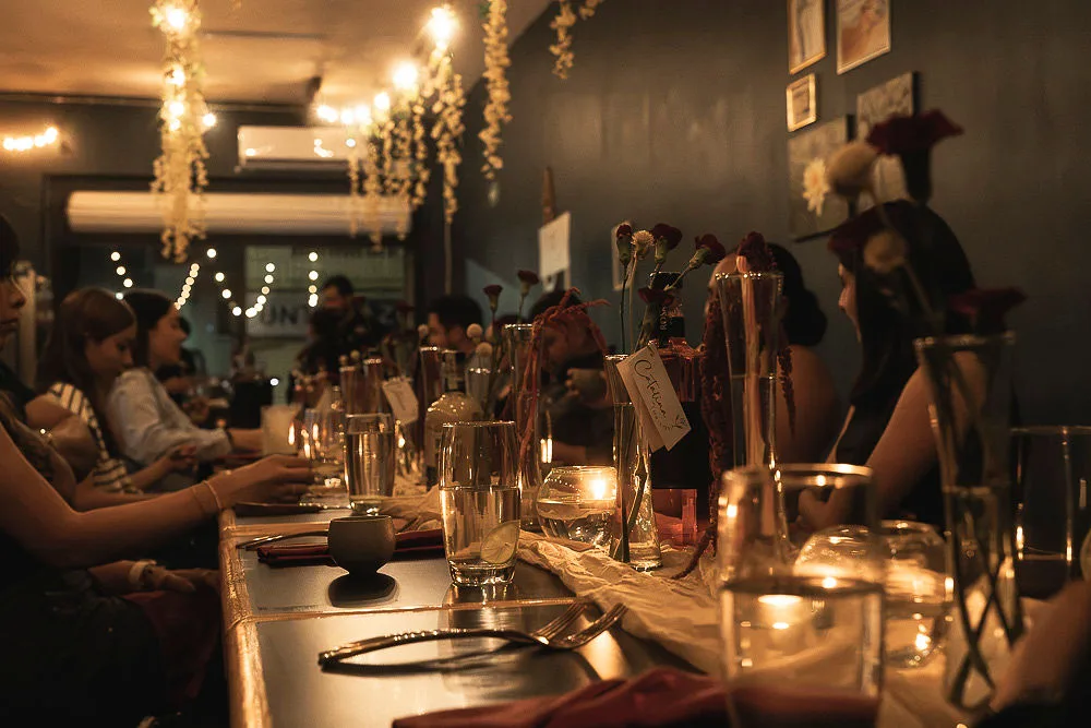 Mesa compartida durante una Cena de Autor en Aroma, con velas y flores en un ambiente íntimo